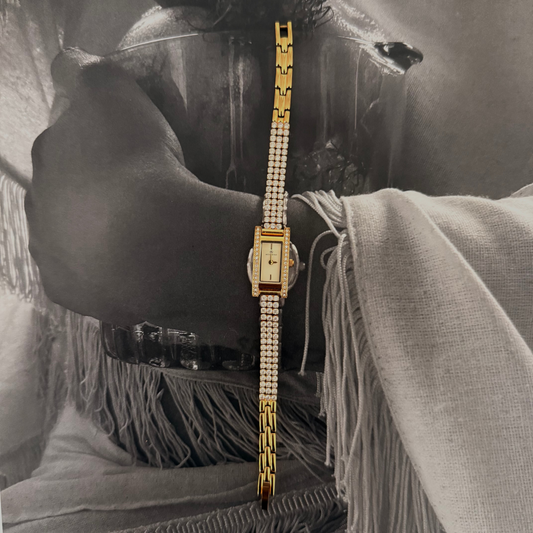 Gold wristwatch with diamond strap on a black and white background
